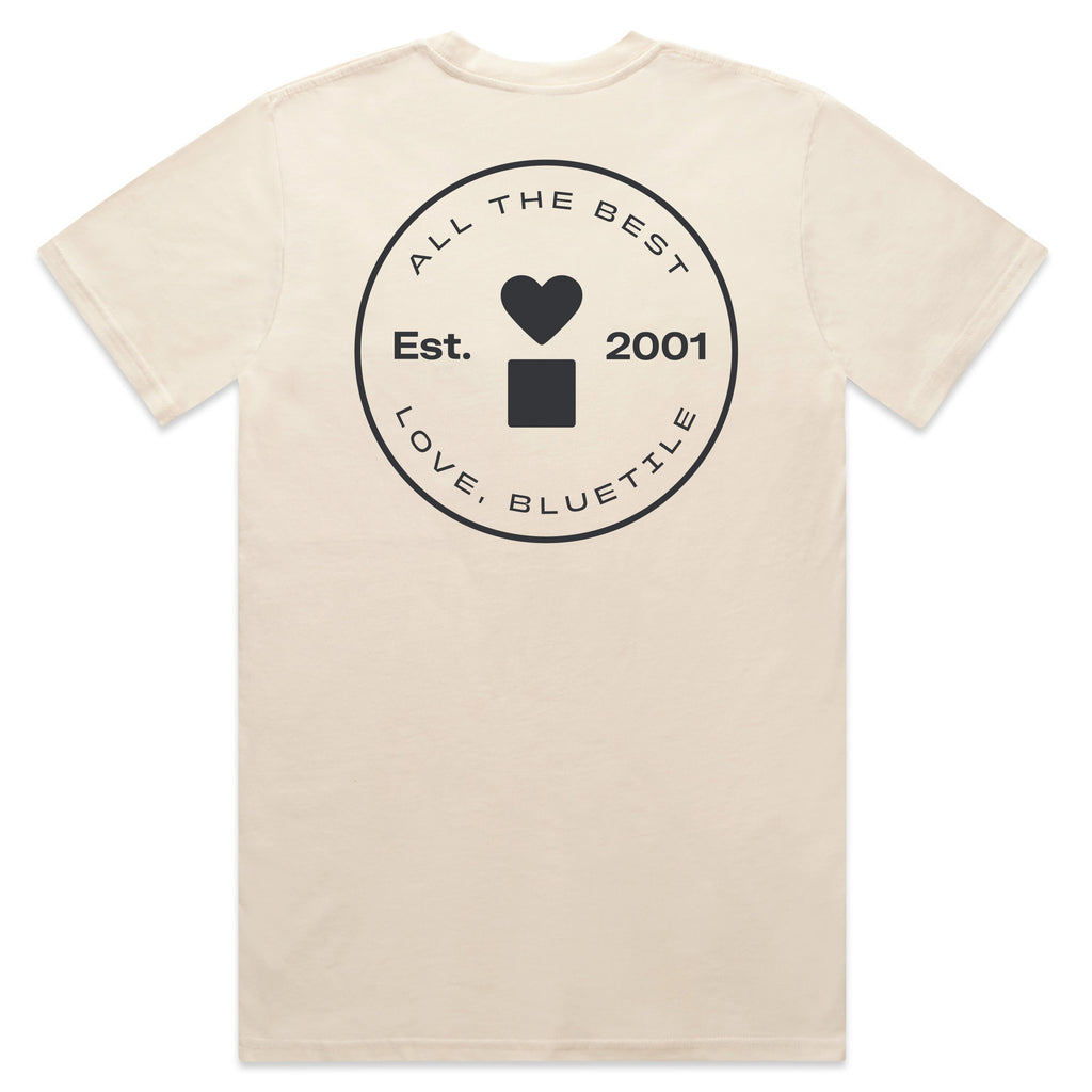 The BLUETILE PRINT STUDIO POCKET TEE ECRU by Bluetile Skateboards is crafted from heavy-weight cotton and available in ecru. It features a circular logo on the back, adorned with a heart and square, alongside hand screen printed text reading "All the Best, Love, Bluetile," and "Est. 2001.