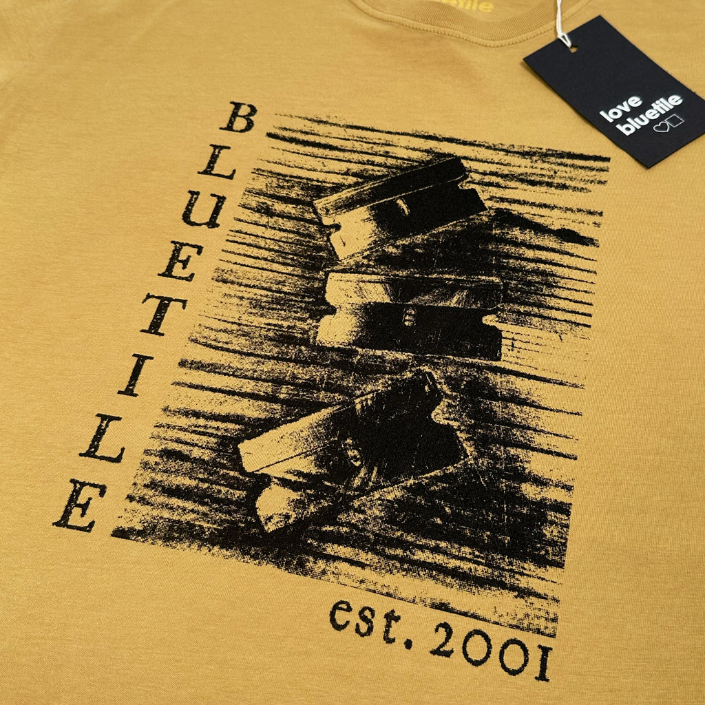 A yellow BLUETILE "RAZORS" TEE FADED MUSTARD t-shirt with the words Bluetile Skateboards on it.
