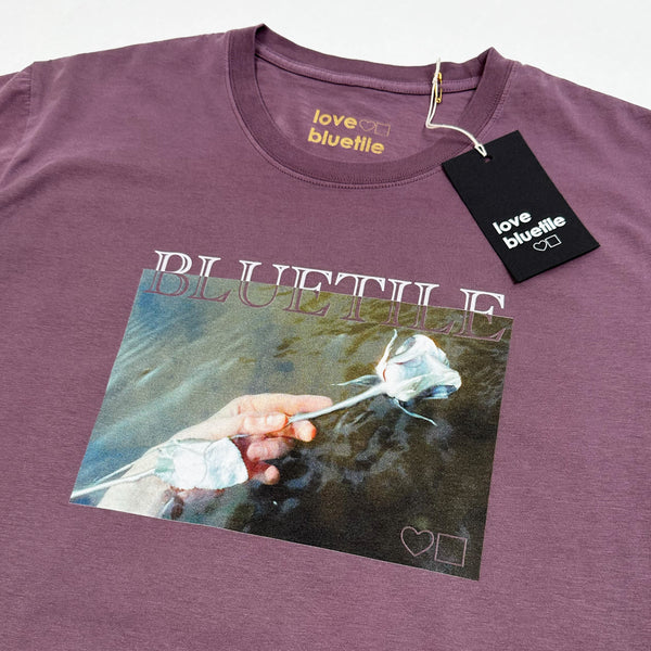 A BLUETILE ROSES TEE FADED MAUVE with a photo of a woman holding a flower.