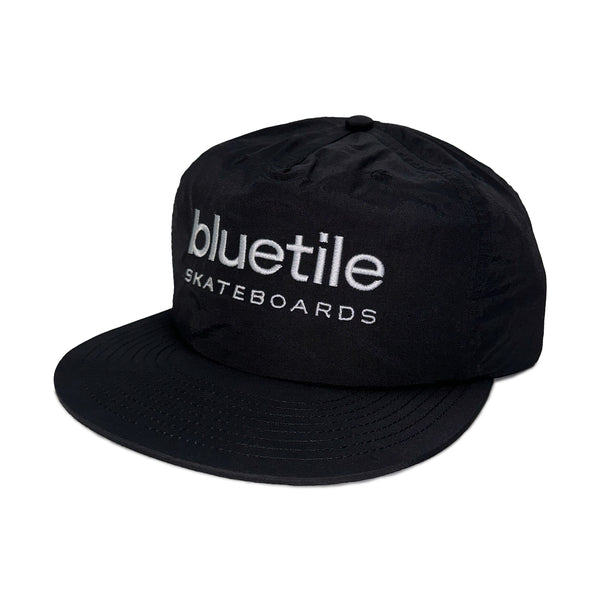 Introducing the BLUETILE LOGO NYLON SURF HAT BLACK by Bluetile Skateboards, a black cap made from recycled nylon and adorned with the embroidered text "bluetile SKATEBOARDS" on the front.