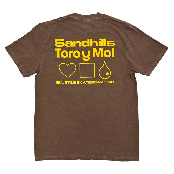 A brown shirt with yellow words "Sandhills Toro Y Moi, Bluetile Skateboarding" and a heart, square, and raindrop.