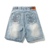 Carpet Co. BUTTER ROACH DENIM SHORTS DISTRESSED INDIGO feature light blue cotton denim, embroidered insect designs on the back pockets, and a brown leather brand patch on the waistband.