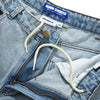 Close-up of Carpet Co. BUTTER ROACH DENIM SHORTS DISTRESSED INDIGO in light blue with a zip fly, baggy fit, drawstring waistband, and visible "DENIM SHORTS" and "Butter" brand labels above the size tag marked "32.