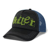 The BUTTER GOODS BREAKDOWN TRUCKER CAP BLACK by Butter Goods is a black and blue 6-panel hat, adorned with the word "Butter" in green stylized lettering on the front panel. Crafted from a cotton nylon blend, this cap features white stitching and a mesh back for enhanced breathability.