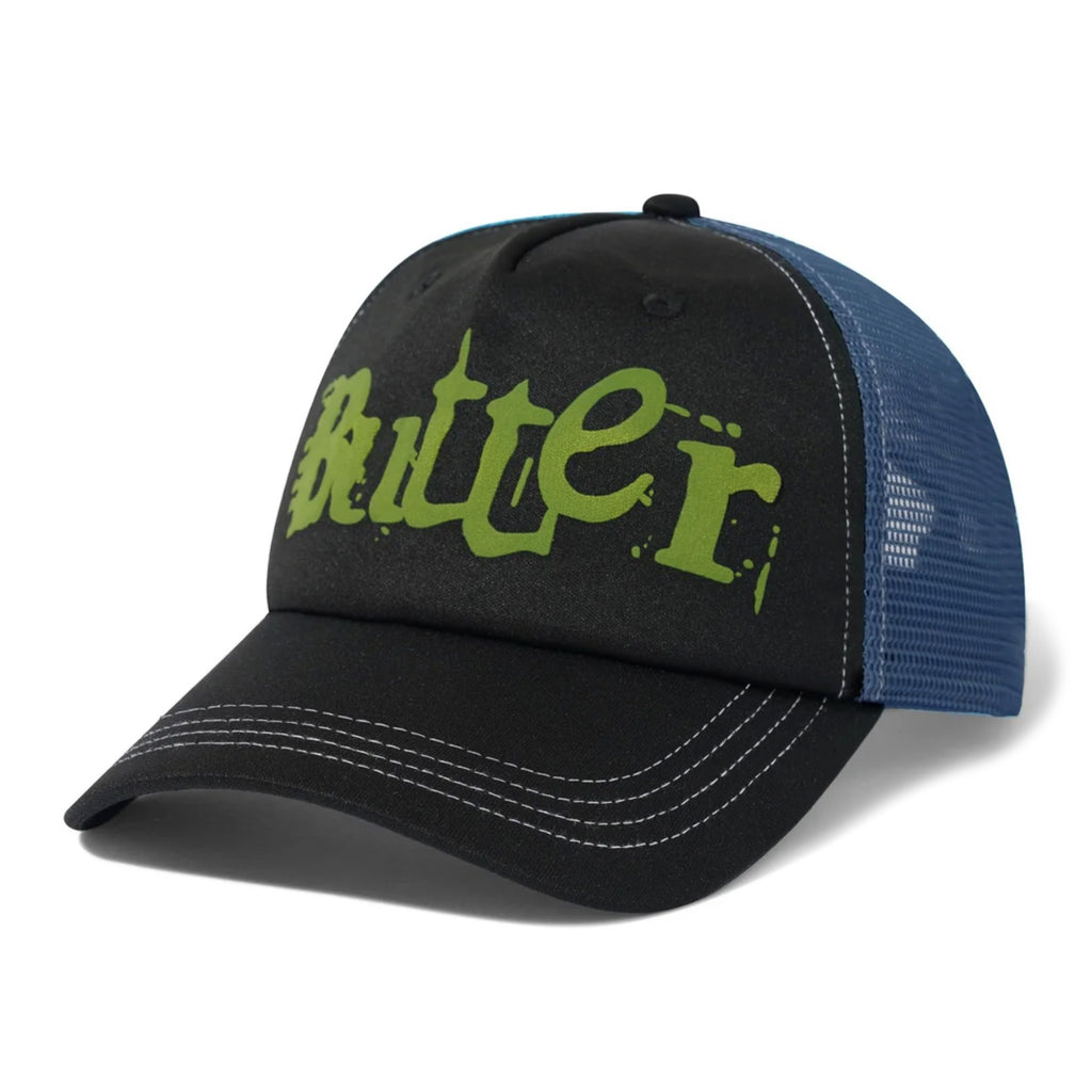 The BUTTER GOODS BREAKDOWN TRUCKER CAP BLACK by Butter Goods is a black and blue 6-panel hat, adorned with the word "Butter" in green stylized lettering on the front panel. Crafted from a cotton nylon blend, this cap features white stitching and a mesh back for enhanced breathability.