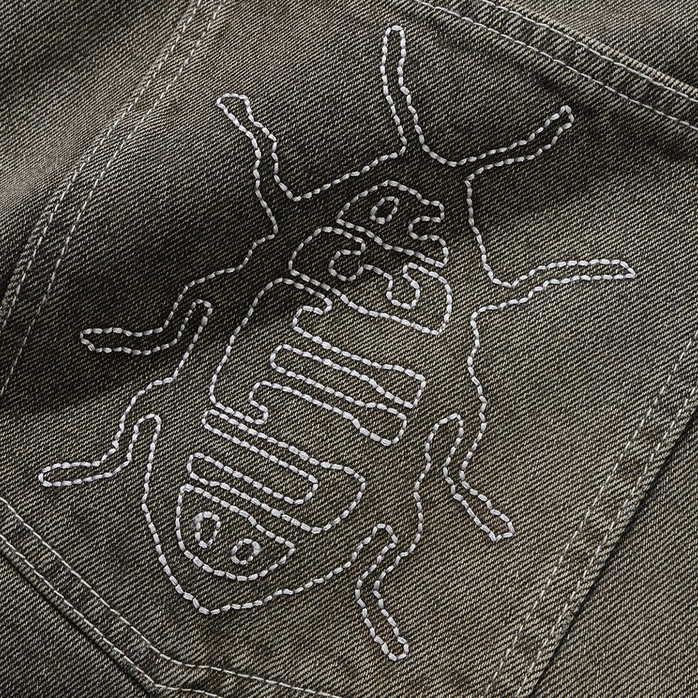 Close-up of black denim fabric with a white embroidered insect outline on the pocket—a signature detail from Butter Goods seen on their Roach Denim Jeans Black Wash.