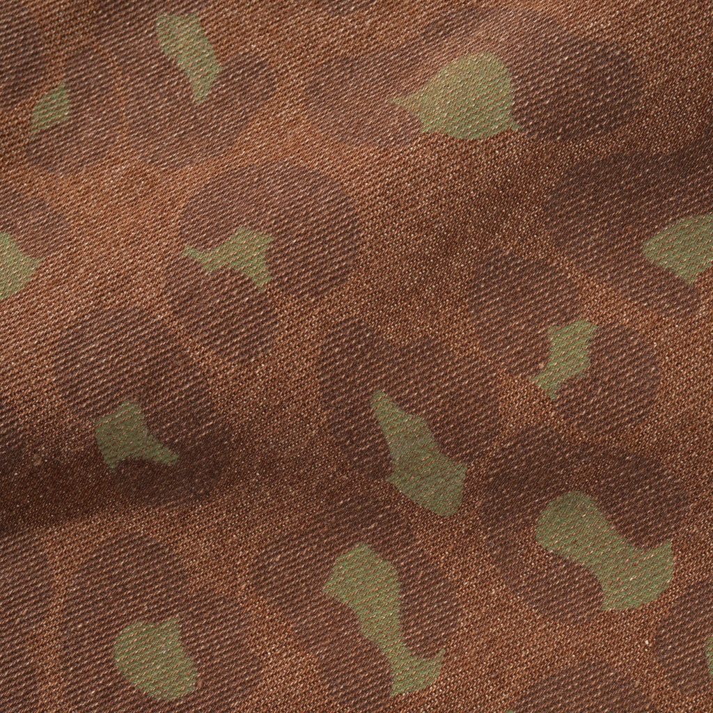 Close-up of fabric with a camouflage pattern in shades of brown and green, reminiscent of BUTTER GOODS LEOPARD DENIM JEANS RUST.