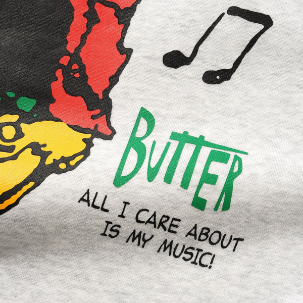 Close-up of cotton polyester fleece on the BUTTER X PEANUTS MUSIC CREWNECK ASH by Butter Goods, featuring colorful screen-printed musical notes, "Butter," and "All I care about is my music!"—perfect for Peanuts fans.