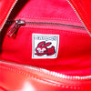 Close-up of the Carpet Co. C-Star Purse Red interior, featuring a zippered pocket and a sewn patch with a cartoon rabbit, the word "carpet," and playful carpet-themed embellishments.