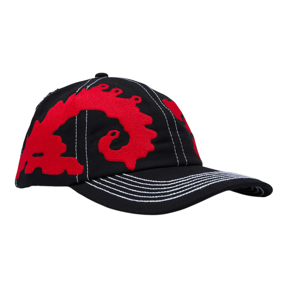 The CARPET CO. DRAGON HAT BLACK by Carpet Co. is a black snapback baseball cap featuring white stitching and a bold red abstract embroidered design on the front and side, offering standout style to enhance any outfit.