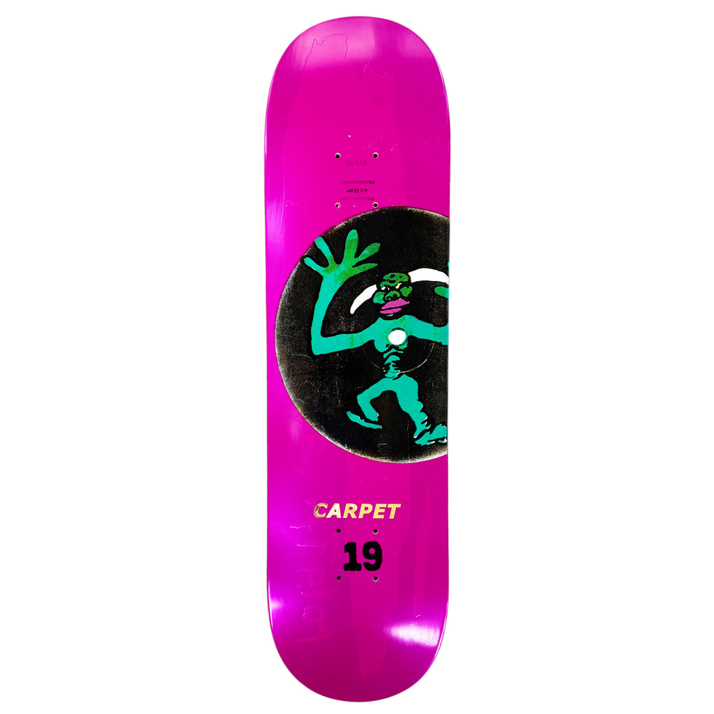 A pink skateboard deck, named CARPET VINYL by Carpet Co., features a green figure with raised hands against a circular black background, evoking ancient Egypt. The text "CARPET" and "19" enhance its design, while an optimal wheelbase ensures smooth rides.