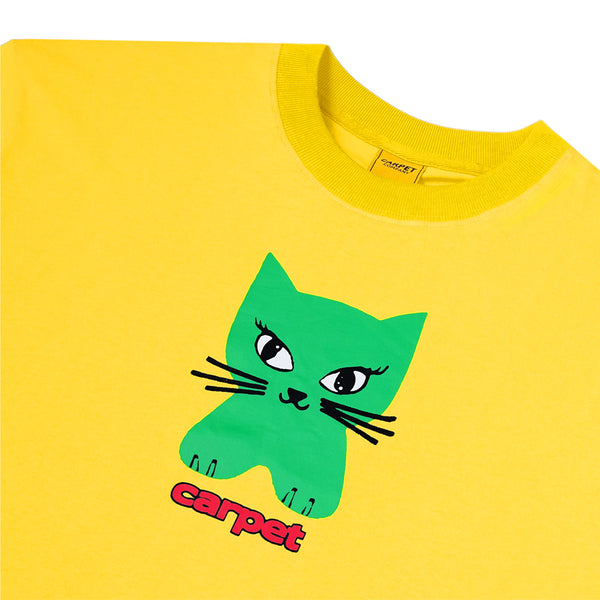 The CARPET CO. CAT TEE YELLOW by Carpet Co. is a yellow cotton t-shirt with a green cartoon cat and bold red “carpet” text screen printed below the graphic.
