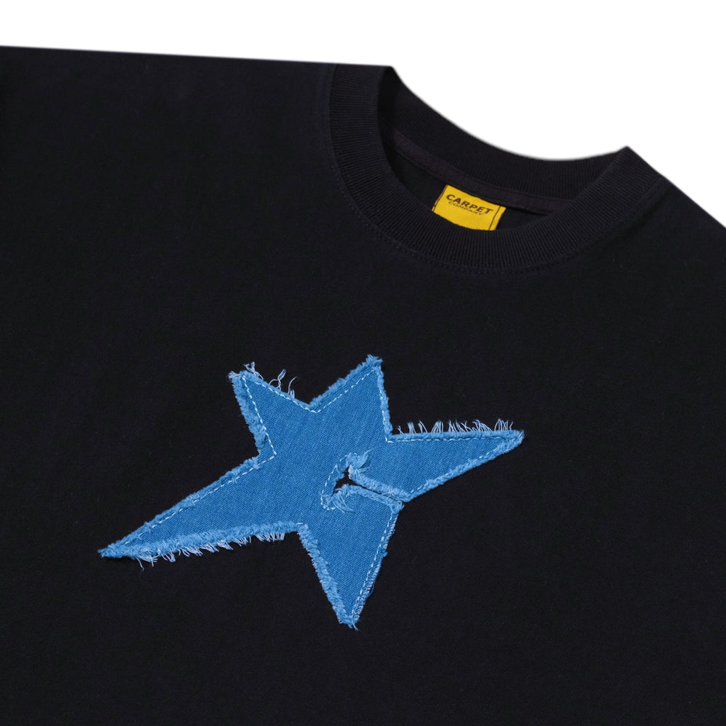 Black tee, known as CARPET CO. C-STAR BLACK from Carpet Co., featuring a large distressed blue star patch on the front against a white background, capturing the brand's edgy style.