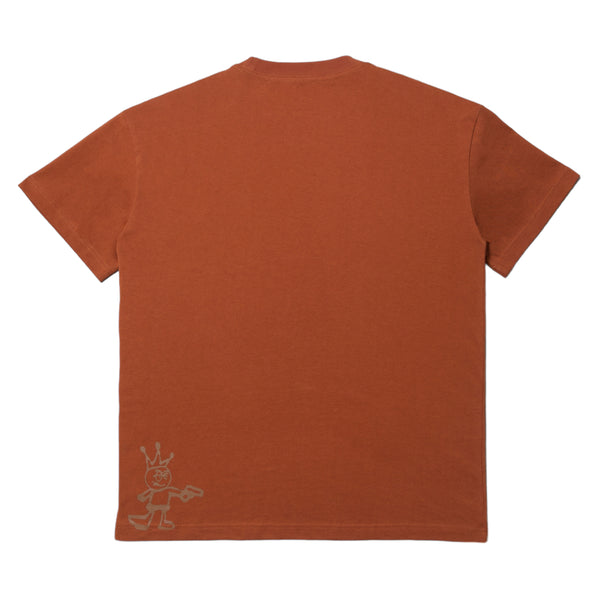 Rust-colored Carpet Co. "Kid" tee with a small white cartoon character graphic on the lower left side, displayed on a plain background.