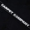 The Carpet Co. FAKE ZIP UP HOODIE BLACK is a black hoodie with double zips and bold white "CARPET COMPANY" text on a stitched strip, giving this standout design a sleek finish.