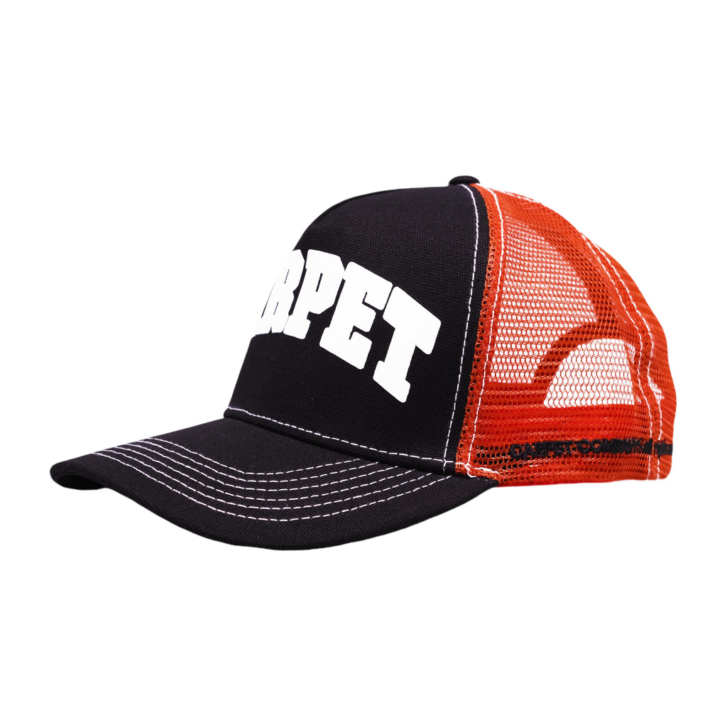 The CARPET COWBOY TRUCKER BLACK by Carpet Co. is a black and orange mesh trucker hat featuring a prominent white "CARPET" logo printed on the front panel, ideal for any carpet cowboy.