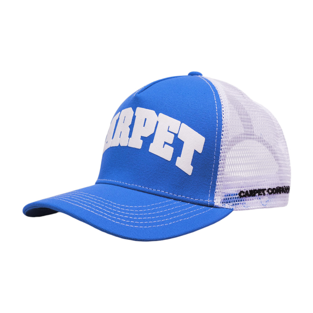 The CARPET COWBOY TRUCKER BLUE by Carpet Co. is a blue and white mesh trucker cap featuring "CARPET" embroidered in large white letters on the front, reminiscent of a classic gas station hat.