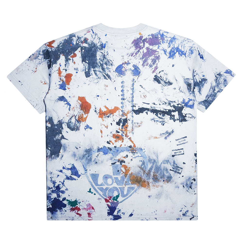The CARPET CO. RAG TEE by Carpet Co. features a white base with multicolored paint splatters, abstract designs, and "LOVE" in bold on the lower back—pair it with black denim for an artistic statement look.