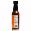 A bottle of CHOCOLATE X NEWKS Chocolate Habanero Hot Sauce by BAKER, featuring a black cap and an orange label with nutrition facts and a barcode, sits against a white background, exuding the cozy charm reminiscent of an egg plush toy.