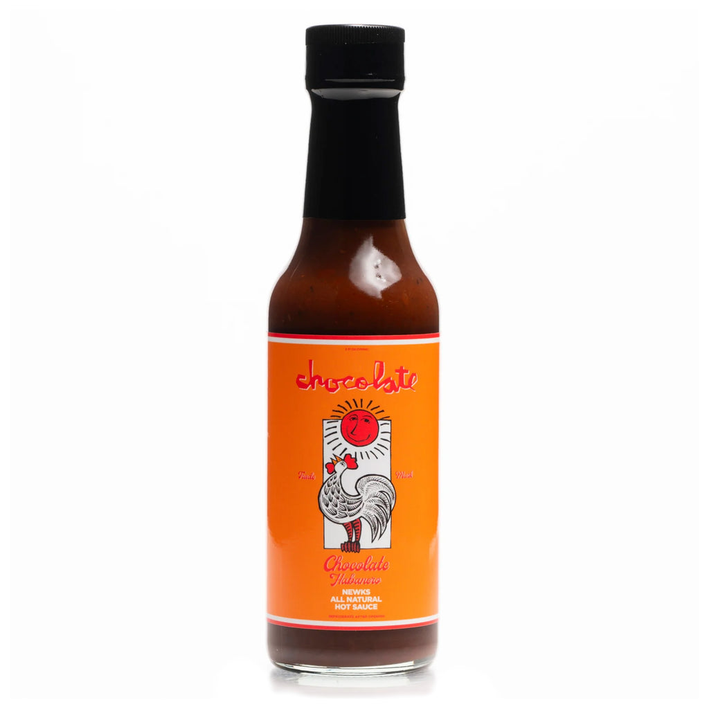 The CHOCOLATE X NEWKS CHOCOLATE HABANERO HOT SAUCE by BAKER features a fiery blend of heat and flavor, encapsulated in a bottle with an orange label and a striking rooster illustration.