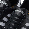 A pair of black and white ADIDAS X FUCKING AWESOME SAMBA sneakers with a logo on them.