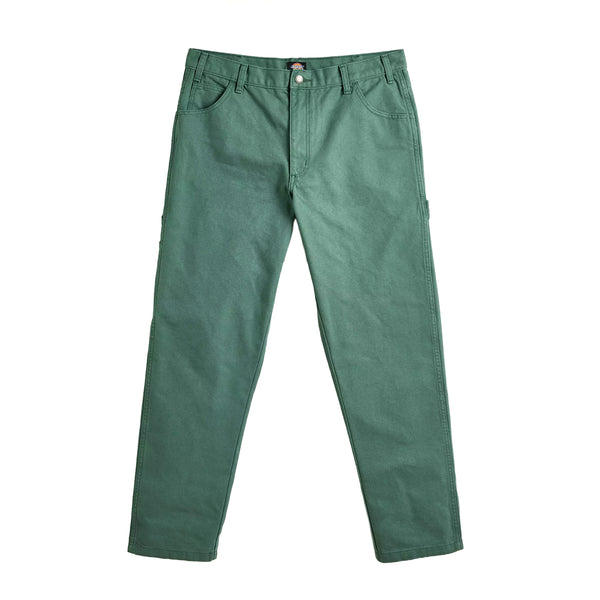 A pair of green DICKIES duck canvas carpenter pants laid flat on a white background, showing the front view with visible utility pockets and a button closure.