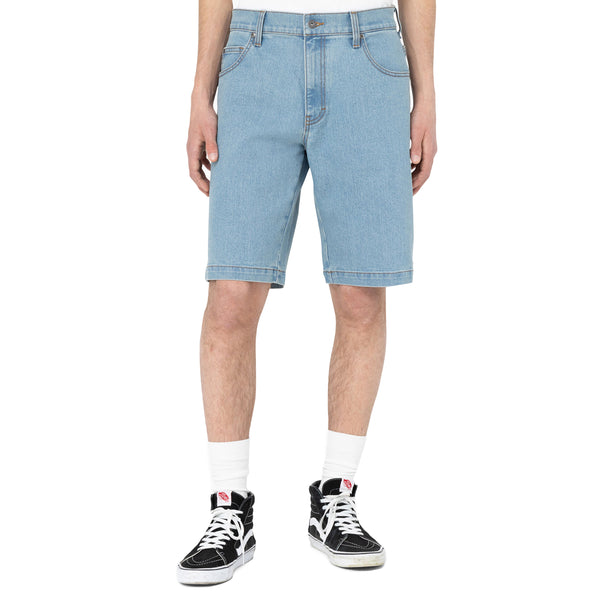 Rear view of a person wearing Dickies Skateboarding Loose Fit Wingville Denim Shorts, white socks, and black and white sneakers, standing against a plain background.