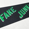 A FAKE JUNK skateboard with the FAKE JUNK GRIPTAPE STENCIL PINE GREEN on it.