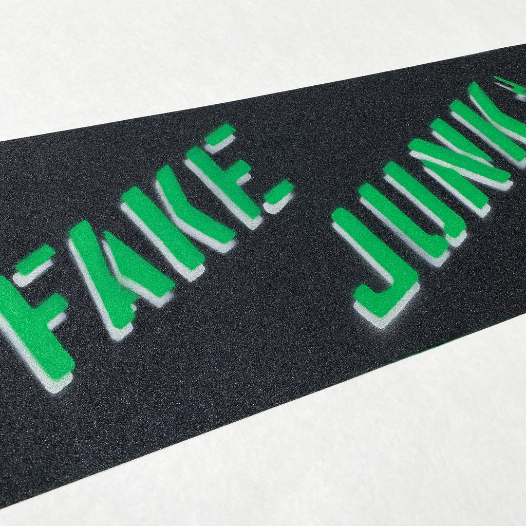 A FAKE JUNK skateboard with the FAKE JUNK GRIPTAPE STENCIL PINE GREEN on it.