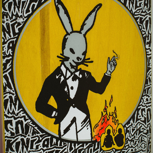 A rabbit in a tuxedo smokes a cigarette in the foreground, with two silhouetted figures near a flame in the background. The image features a graffiti-style black and white text border that reads "FUCKING AWESOME," reminiscent of an edgy class photo. The product is called FUCKING AWESOME THE COMEDIAN by FUCKING AWESOME.