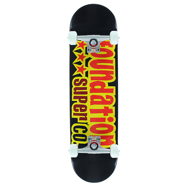 A FOUNDATION skateboard with black grip tape on top and a yellow, red, and black graphic design with the text "foundation star & moon" on the underside.