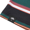 Close-up of a fabric corner featuring horizontal green, burgundy, white, and black stripes with a small black tag showcasing an embroidered umbrella logo. The HELAS RAYURES TEE GREEN / BLACK by HELAS is crafted from 100% cotton for comfort and style.