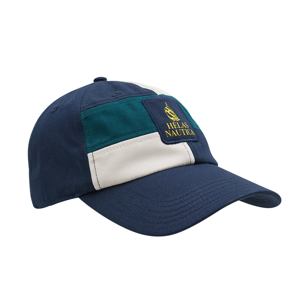 A dark navy patchwork strapback cap featuring green and beige accents, adorned with a "Hellas Nautika" logo and an anchor emblem on the front panel. This is the HELAS X NAUTICA AUBERT STRAPBACK CAP DARK NAVY by HELAS.