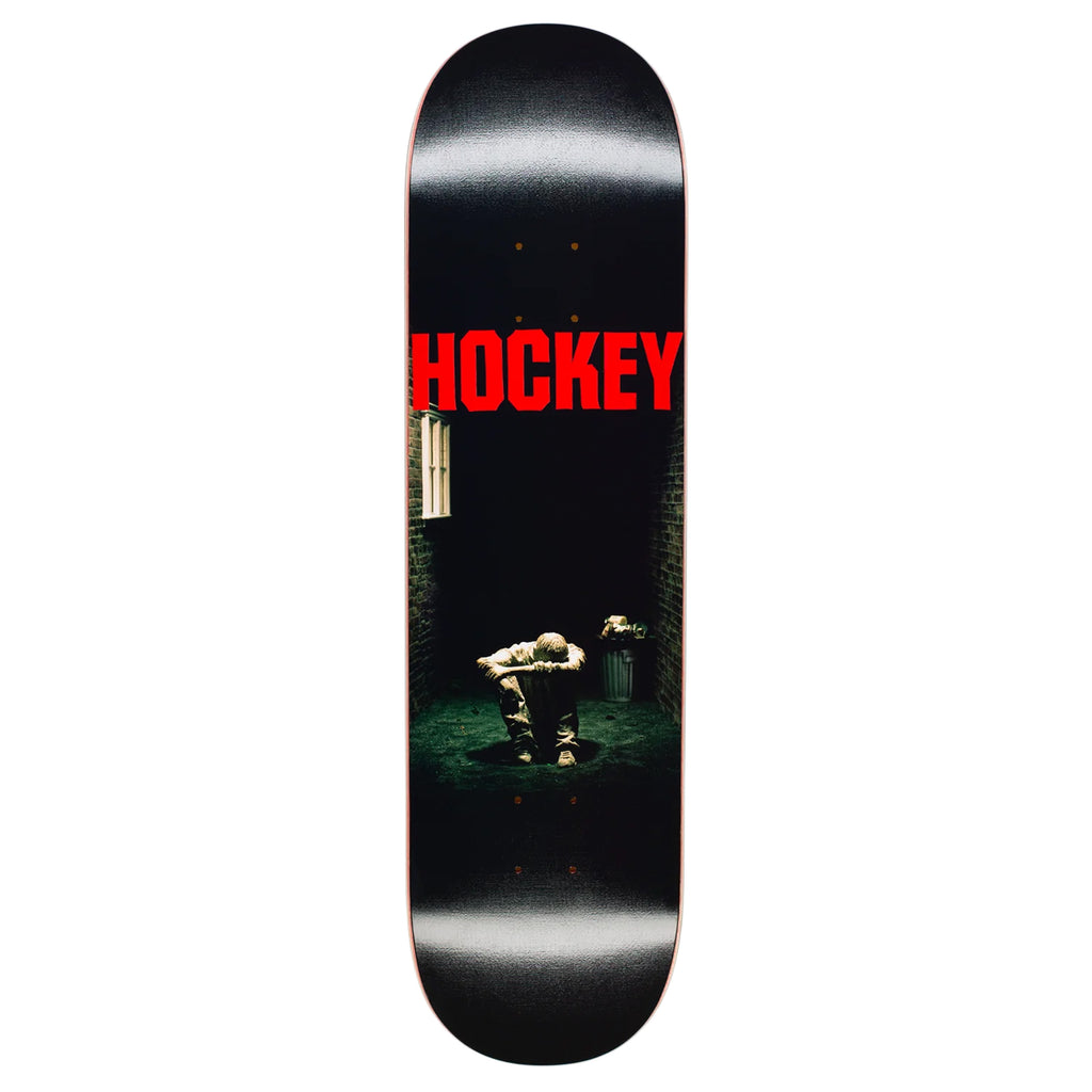 HOCKEY HOCKEY STILL MISSING skateboard deck with a dark, indoor scene of a person sitting on a chair, back facing the viewer, and the word "HOCKEY" in bold red letters at the top. Features a premium digital print that enhances its striking graphic.