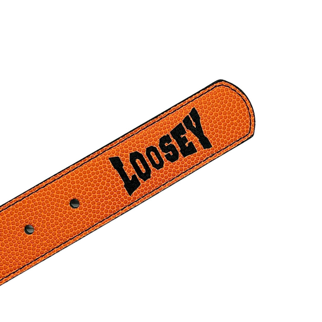 Close-up of an orange textured belt end featuring a sleek buckle, with "LOOSEY ISHOD WAIR PRO" printed in bold black capital letters.