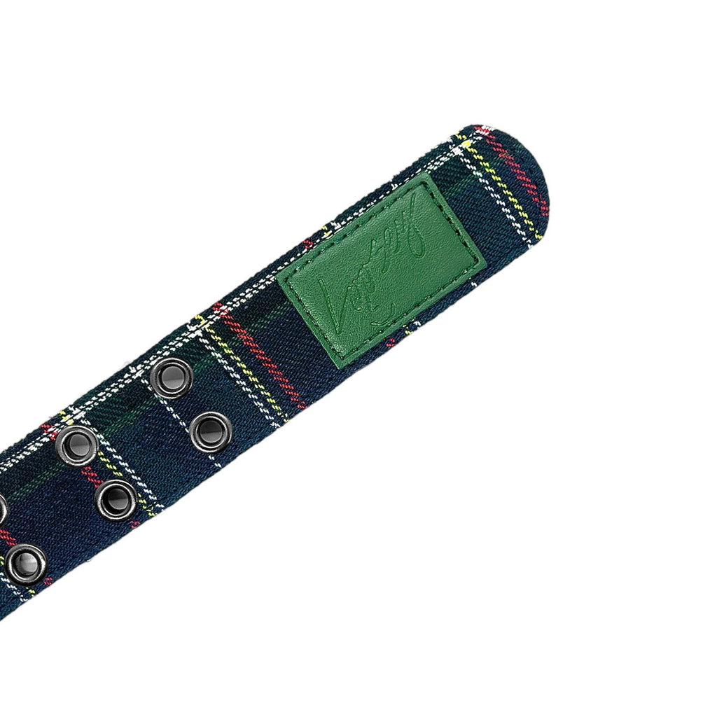 The LOOSEY PLAID GROMMET HOLE BELT by Loosey is showcased against a white background, boasting a red checkered pattern with metal grommets and a green leather patch. Elegant black faux leather details complete its sophisticated look.