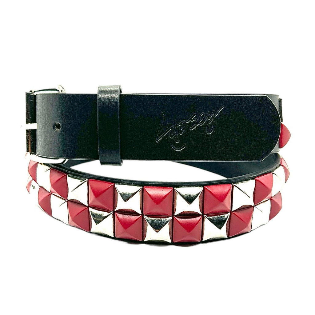 The LOOSEY RED CHECKERED STUD FINDER is a black faux leather belt by Loosey, featuring red and silver pyramid studs, gold grommet rings, and a metal buckle with an engraved signature on the loop.