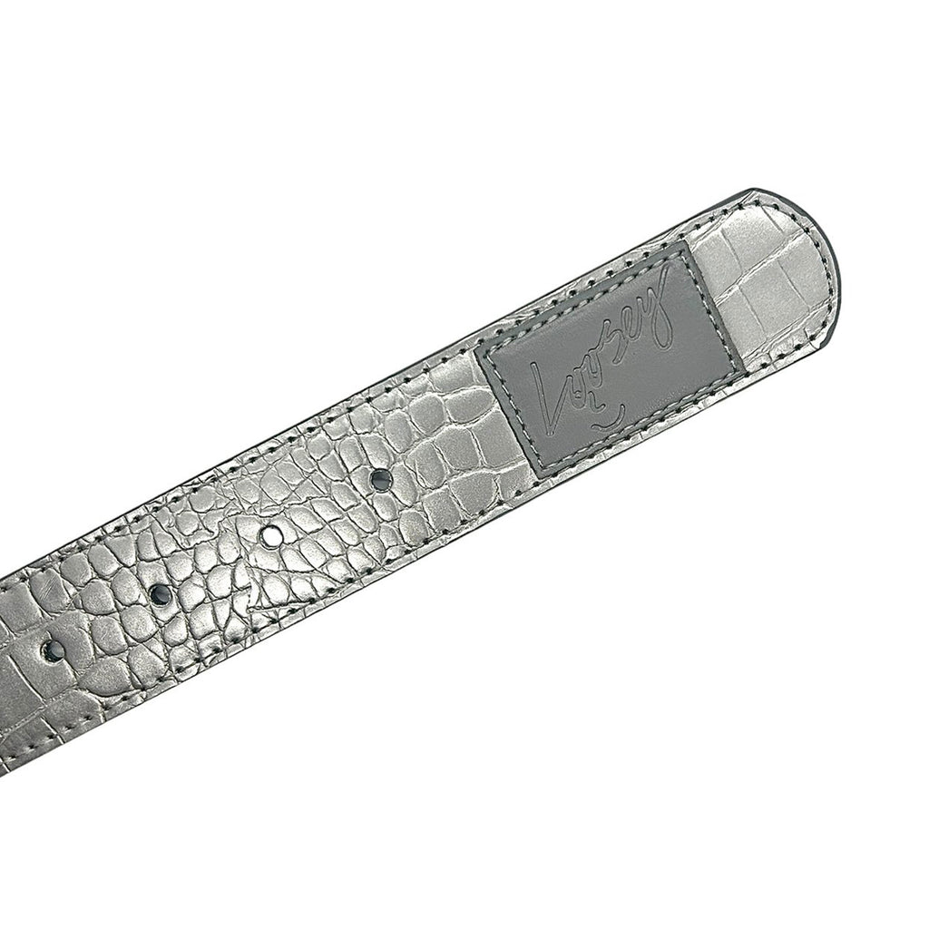 The LOOSEY CROC SKIN BELT SILVER by Loosey is a faux leather belt with a silver textured finish and a rectangular gold buckle adorned with engraved writing.