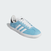 A shoe designed with the classic style of ADIDAS, featuring the colors Crystal White, Core Black, and Better Scarlet, called the ADIDAS X MNUFC X FAMILIA GAZELLE ADV.