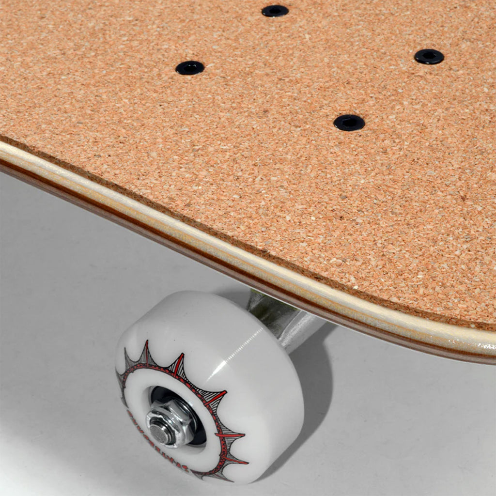 Close-up of a skateboard wheel with a white and red design from the KARL WATSON MY FIRST SKATEBOARD FRIENDS MINI COMPLETE for kids, attached to a board with a cork surface and black bolts.