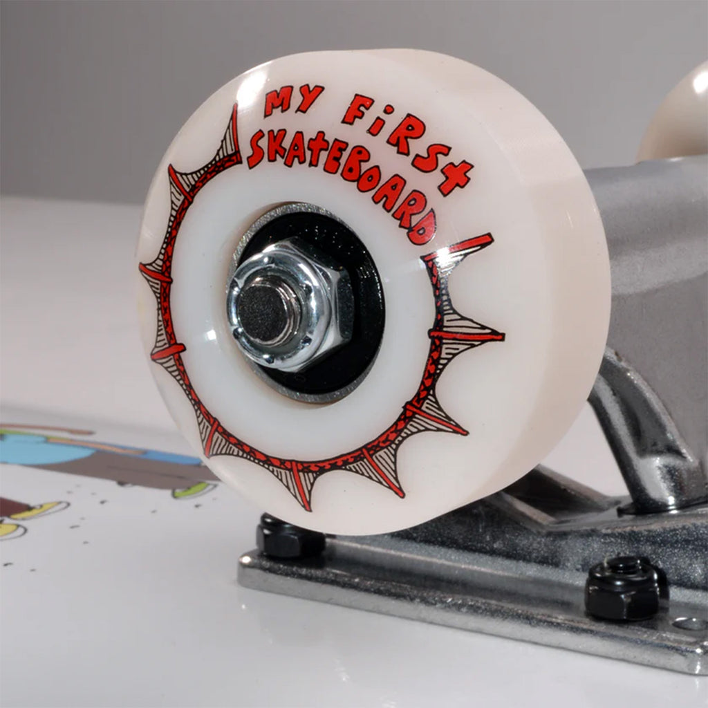 Close-up of a skateboard wheel attached to a silver truck with "MY FIRST SKATEBOARD FRIENDS MINI COMPLETE" by KARL WATSON in red lettering, perfect for kids.