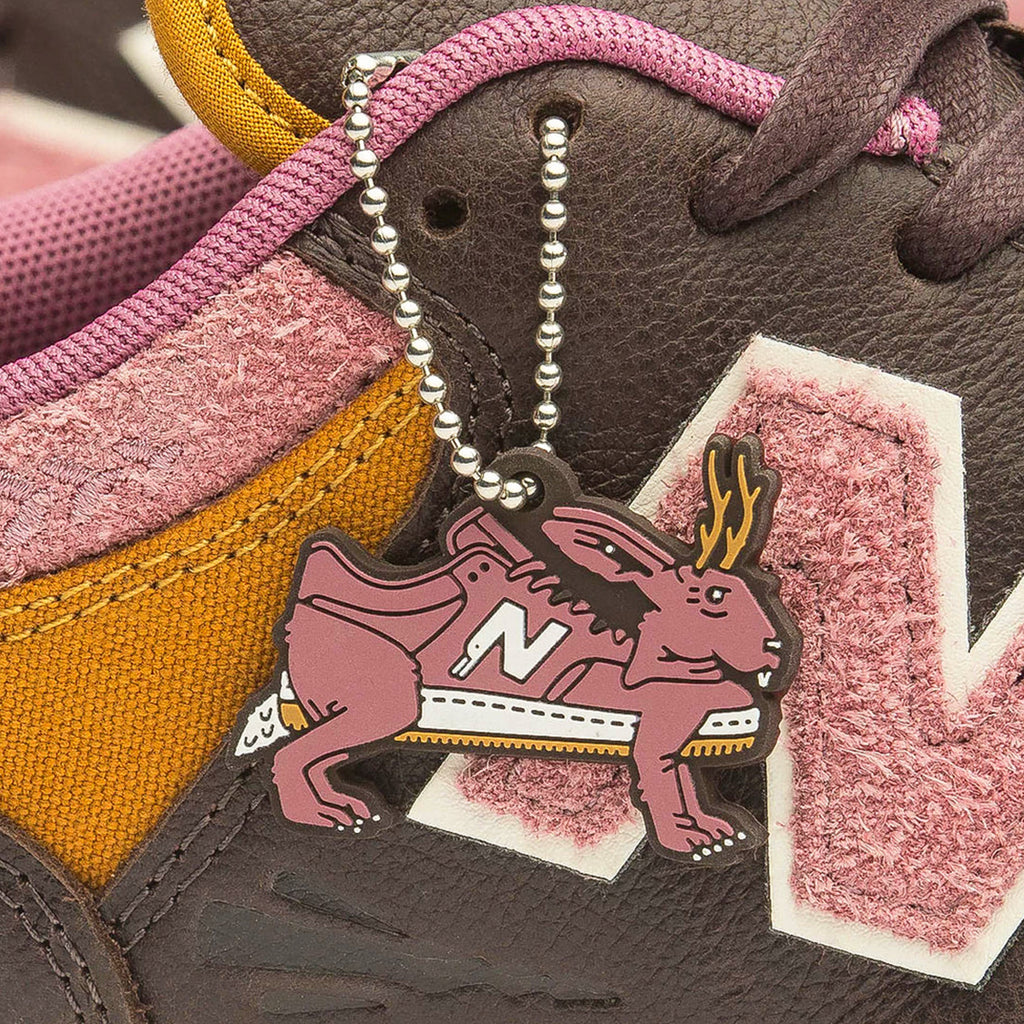 Close-up of a sneaker with a pink and brown moose keychain attached to its laces, featuring the prominent NB Numeric 480 x 303 Boards x Jeremy Fish shoe brand logo.