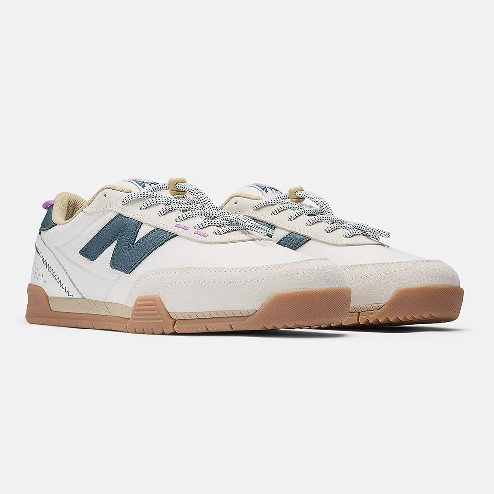A pair of NB NUMERIC 440 V2 Trail Low skate shoes in Sea Salt/Deep Ocean with white uppers, tan gum soles, grey and black laces, blue "N" logos on the sides, and light purple accents.