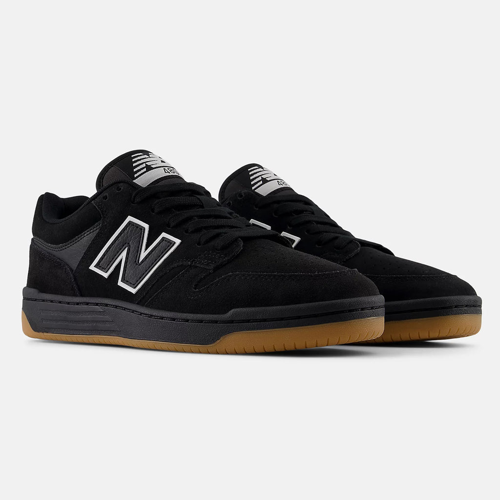 A pair of black NB NUMERIC NB NUMERIC 480 BLACK / WHITE / GUM sneakers with gum soles, showcasing a large "N" logo on the side and a striped tongue design, positioned on a plain white background.