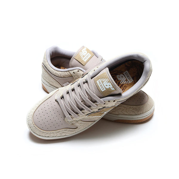 Brown and white NB Numeric x Premier 480 sneakers with a textured sole and embossed detailing, featuring FuelCell foam for added comfort, placed on a white background.