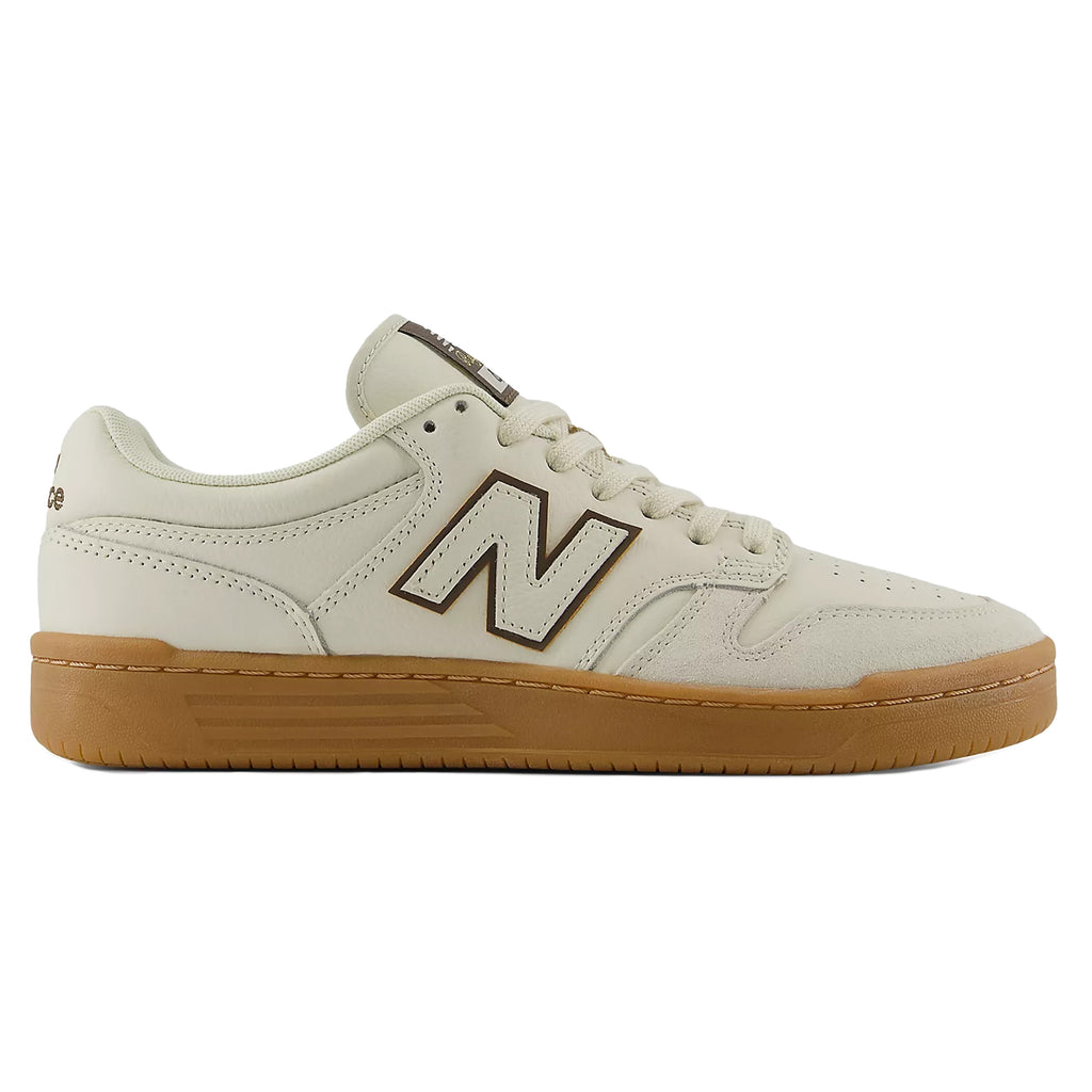 A pair of NB NUMERIC ANDREW REYNOLDS 480 SEA SALT / BROWN sneakers from NB NUMERIC, featuring a beige color with a contrasting brown "N" logo and white laces. These shoes include an ABZORB insole, a chunky brown rubber sole, and boast a low-top design.