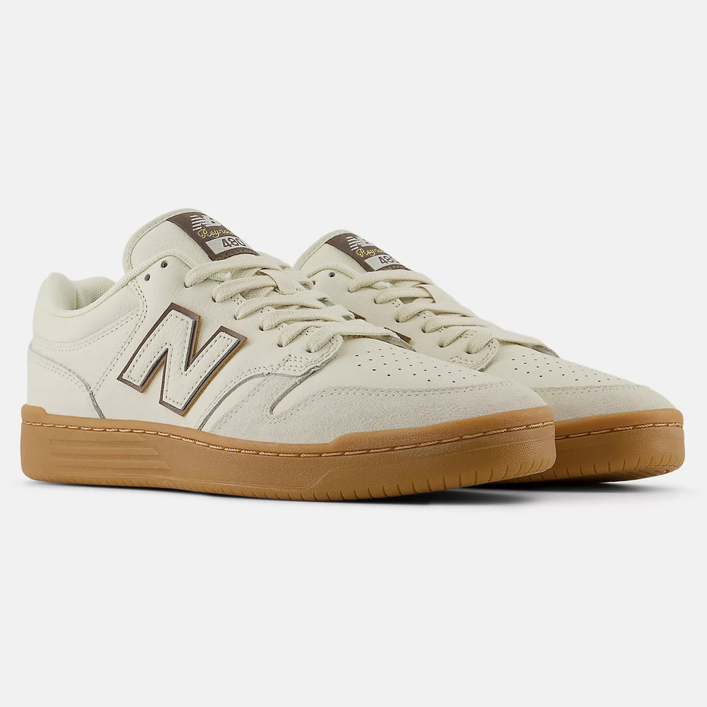 Pair of NB NUMERIC Andrew Reynolds 480 sneakers in sea salt with brown accents, featuring the brand's logo on the side and a brown rubber sole enhanced with ABZORB in-sole cushioning. Shoes are photographed on a white background.