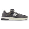 The NB NUMERIC "GREY DAYS" REYNOLDS 933 in dark grey and white features a cream sole, white laces, and a signature "N" logo. Premium cushioning enhances comfort. Shown in profile view against a white background.