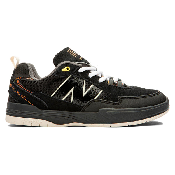 The NB NUMERIC X ROLAND 808 TIAGO BLACK / ORANGE sneaker, designed by NB NUMERIC, features a sleek black upper with white laces, a prominent "N" logo, vibrant orange accents, and a beige sole. The design combines both suede and mesh materials to offer enhanced style and comfort.