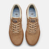 A pair of beige sneakers, resembling the NB NUMERIC X MUSEUM 272 WHEAT / BROWN by NB NUMERIC, with perforated toe boxes and brown laces. The insoles have a blue pattern and the text “ENTER THE MUSEUM” along with a geometric graphic.